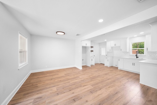 2415 Falls Dr, Dallas, TX 75211 - unfurnished living room with light wood finished floors, recessed lighting, baseboards, and a sink