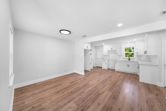 2415 Falls Dr, Dallas, TX 75211 - unfurnished living room with light wood-style floors, recessed lighting, baseboards, and a sink