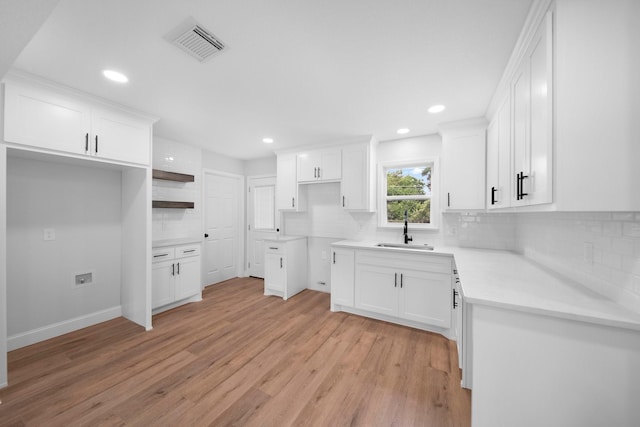 2415 Falls Dr, Dallas, TX 75211 - kitchen featuring backsplash, light wood finished floors, a sink, recessed lighting, and white cabinets