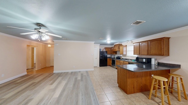 2008 Pine Knot Dr, Heartland, TX 75126 - kitchen with black appliances, brown cabinetry, a peninsula, ornamental molding, and dark countertops