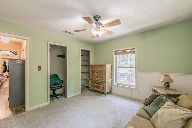 1055 Miller Rd, Reno, TX 76020 - living area featuring ceiling fan, a textured ceiling, wainscoting, and carpet
