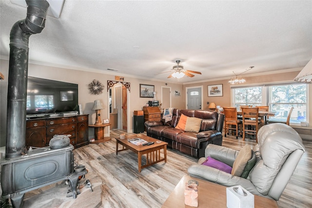 1055 Miller Rd, Reno, TX 76020 - living room featuring light wood finished floors, ceiling fan, a wood stove, crown molding, and a chandelier