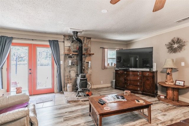 1055 Miller Rd, Reno, TX 76020 - living area featuring crown molding, a textured ceiling, a wood stove, wood finished floors, and french doors