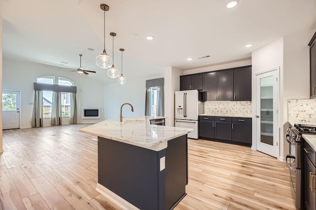 17204 Clover Dr, Celina, TX 75009 - kitchen featuring white refrigerator with ice dispenser, gas range, open floor plan, backsplash, and light stone counters
