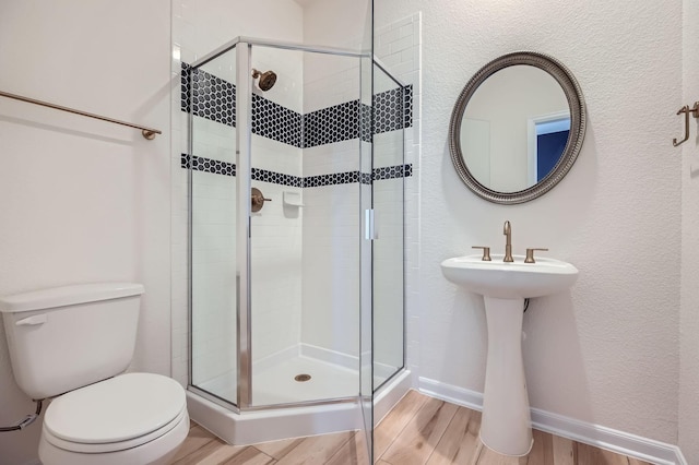 17204 Clover Dr, Celina, TX 75009 - bathroom with toilet, wood finished floors, a stall shower, baseboards, and a textured wall