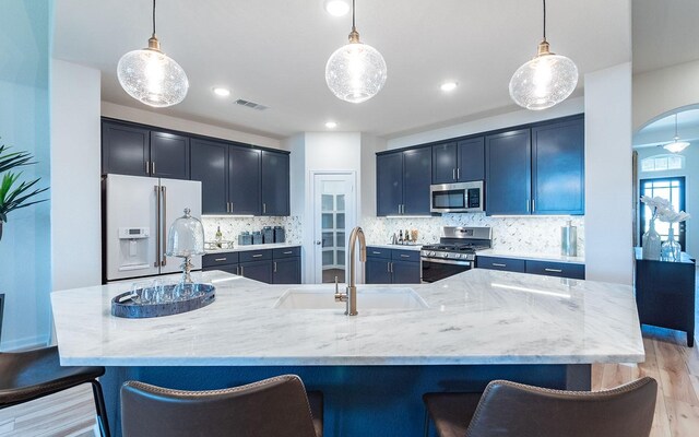 17204 Clover Dr, Celina, TX 75009 - kitchen with stainless steel appliances, a sink, light wood-style floors, a breakfast bar, and light stone countertops