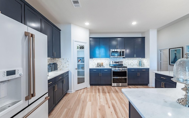 17204 Clover Dr, Celina, TX 75009 - kitchen featuring stainless steel appliances, light wood-style flooring, backsplash, recessed lighting, and light stone counters