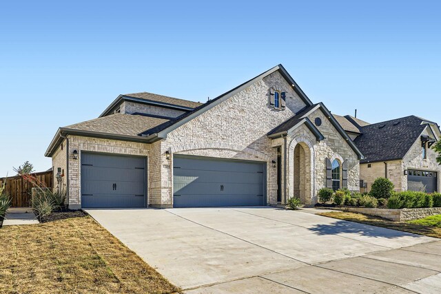 17204 Clover Dr, Celina, TX 75009 - french country inspired facade featuring an attached garage, concrete driveway, brick siding, and roof with shingles