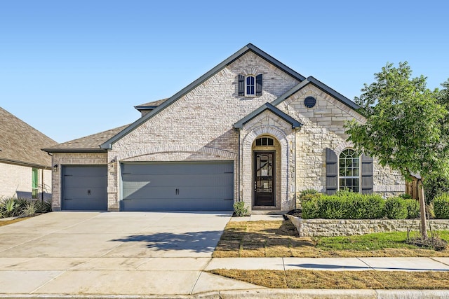 17204 Clover Dr, Celina, TX 75009 - french country inspired facade with a garage, concrete driveway, stone siding, and brick siding
