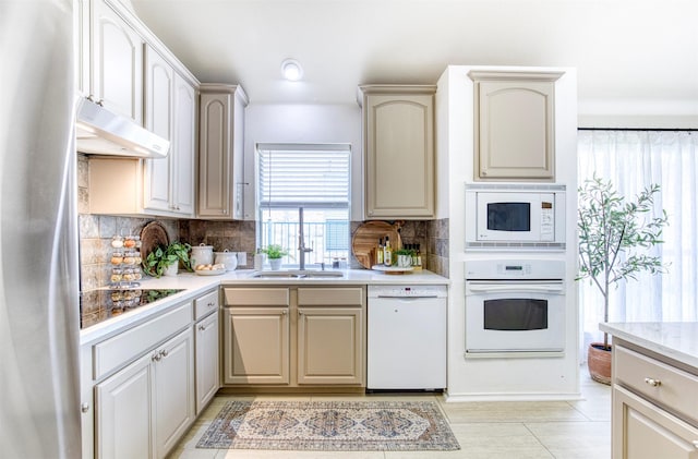 11471 Balcones Dr, Frisco, TX 75033 - kitchen with white appliances, under cabinet range hood, light countertops, a sink, and backsplash
