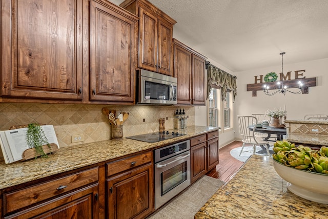 1702 Clarke Springs Dr, Allen, TX 75002 - kitchen featuring stainless steel appliances, light wood-style flooring, a chandelier, backsplash, and light stone counters