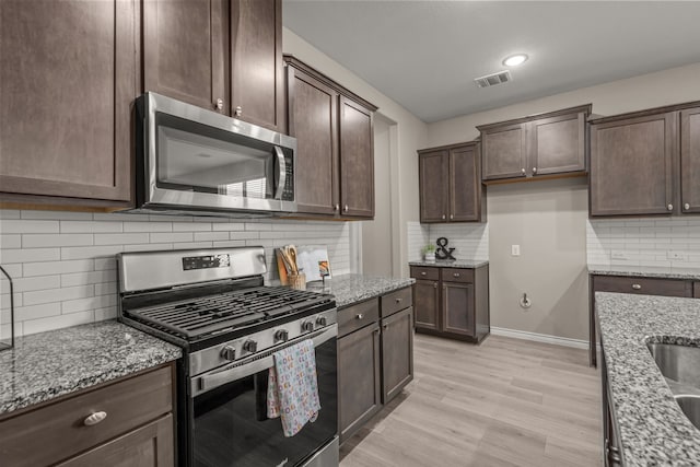 1601 Bennington Ln, Celina, TX 75009 - kitchen with stainless steel appliances, light stone counters, dark brown cabinets, backsplash, and recessed lighting