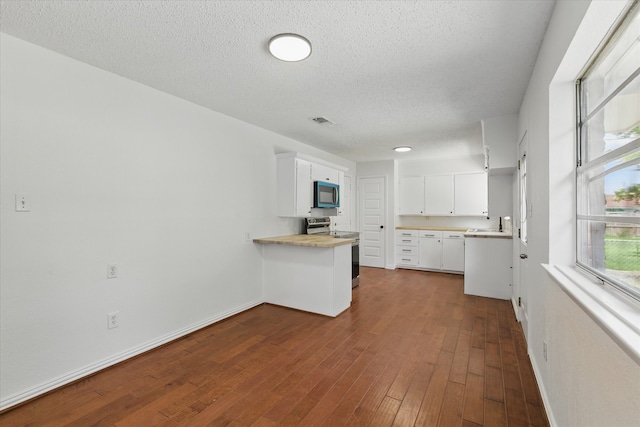 3622 Emerald Dr, Mesquite, TX 75150 - kitchen featuring appliances with stainless steel finishes, white cabinets, dark wood-style floors, a peninsula, and light countertops