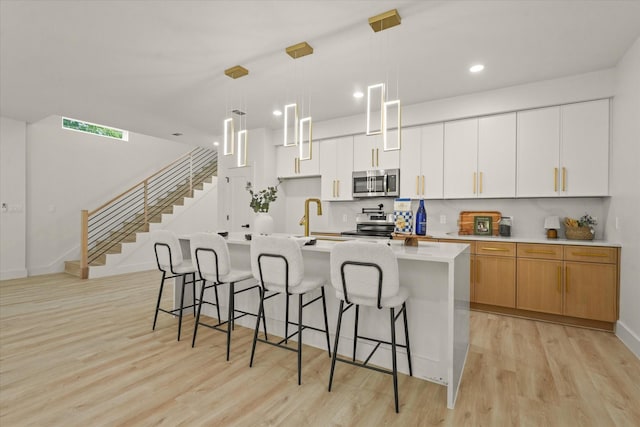 1344 Compton St, Dallas, TX 75203 - kitchen with stainless steel appliances, a kitchen island with sink, light wood-style flooring, a kitchen breakfast bar, and recessed lighting