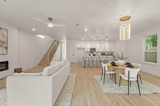 1344 Compton St, Dallas, TX 75203 - living room featuring light wood finished floors, ceiling fan, stairs, baseboards, and recessed lighting