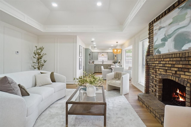 6420 Green Ridge Dr, Watauga, TX 76148 - living area with light wood finished floors, a fireplace, a tray ceiling, and crown molding