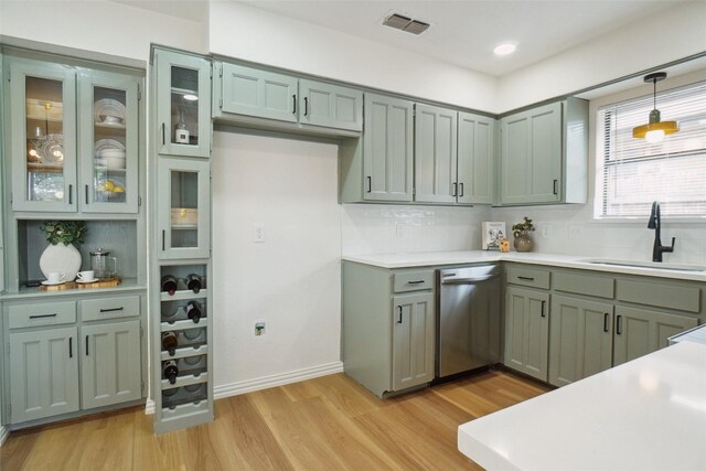 6420 Green Ridge Dr, Watauga, TX 76148 - kitchen featuring stainless steel dishwasher, a sink, light wood-type flooring, decorative backsplash, and light countertops