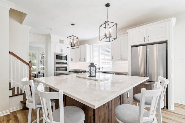 4804 Arbor Glen Dr, Mckinney, TX 75072 - kitchen featuring appliances with stainless steel finishes, light stone countertops, light wood-type flooring, white cabinets, and a center island