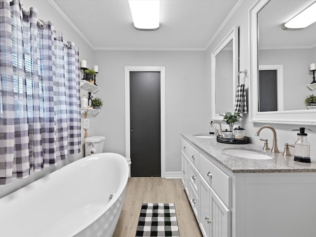 910 N Mill St, Bowie, TX 76230 - bathroom featuring wood finished floors, a freestanding tub, double vanity, and ornamental molding