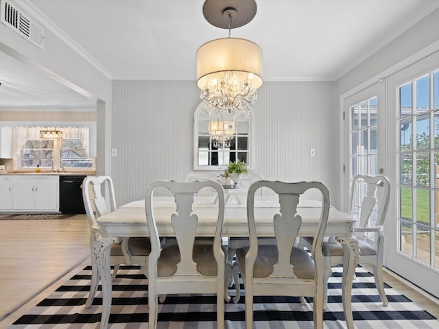 910 N Mill St, Bowie, TX 76230 - dining area featuring a chandelier, light wood finished floors, and crown molding