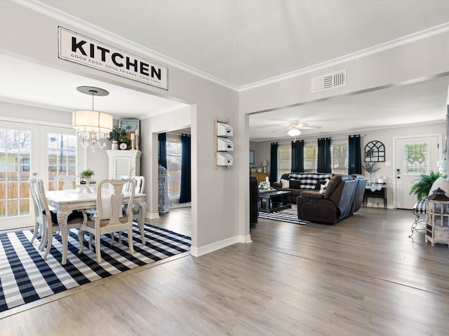 910 N Mill St, Bowie, TX 76230 - dining space with wood finished floors, crown molding, a chandelier, french doors, and ceiling fan