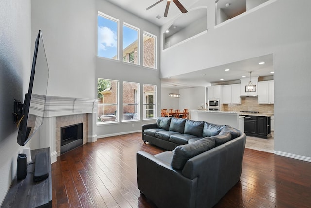 14877 Snowshill Dr, Frisco, TX 75035 - living area with ceiling fan, hardwood / wood-style flooring, a towering ceiling, baseboards, and a tile fireplace