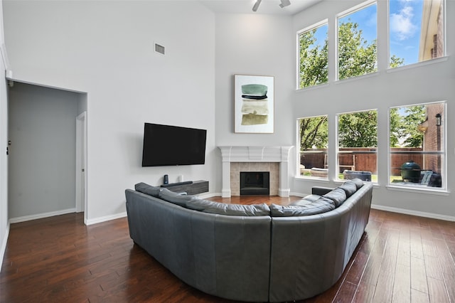 14877 Snowshill Dr, Frisco, TX 75035 - living area featuring a high ceiling, dark wood-type flooring, a tiled fireplace, baseboards, and a ceiling fan