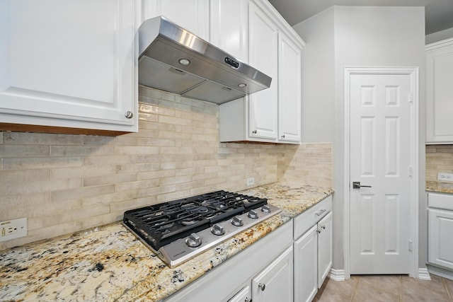 14877 Snowshill Dr, Frisco, TX 75035 - kitchen with under cabinet range hood, stainless steel gas cooktop, white cabinetry, decorative backsplash, and light stone counters