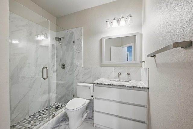 14877 Snowshill Dr, Frisco, TX 75035 - bathroom featuring toilet, a marble finish shower, vanity, tile walls, and a textured wall