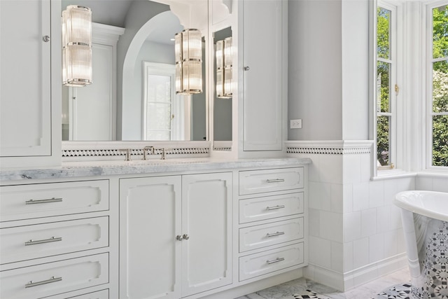 4400 Belfort Pl, Highland Park, TX 75205 - bathroom with tile walls, plenty of natural light, marble look tiles, vanity, and a wainscoted wall