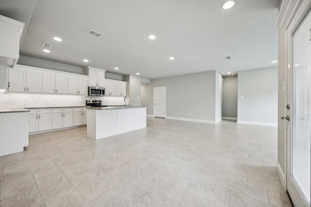 129 Braves Way, Lavon, TX 75166 - kitchen with appliances with stainless steel finishes, decorative backsplash, white cabinets, a sink, and a center island with sink