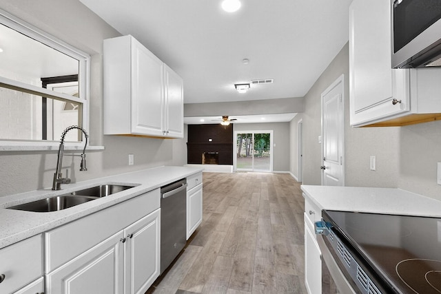6821 Mickey Dr, Watauga, TX 76148 - kitchen featuring appliances with stainless steel finishes, a sink, a ceiling fan, white cabinetry, and light wood-style floors