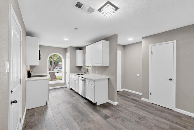 6821 Mickey Dr, Watauga, TX 76148 - kitchen featuring stainless steel dishwasher, light countertops, wood finished floors, white cabinetry, and recessed lighting