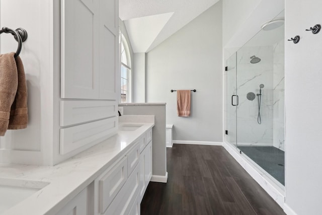 7314 Glenstone St, Rowlett, TX 75089 - bathroom with a marble finish shower, double vanity, wood finished floors, baseboards, and vaulted ceiling