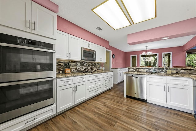 1200 Old Decatur Rd, Decatur, TX 76234 - kitchen with appliances with stainless steel finishes, decorative backsplash, a chandelier, white cabinetry, and dark wood-style flooring