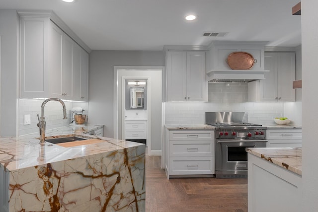 6867 Mossvine Dr, Dallas, TX 75254 - kitchen featuring premium stove, light stone countertops, recessed lighting, a sink, and decorative backsplash