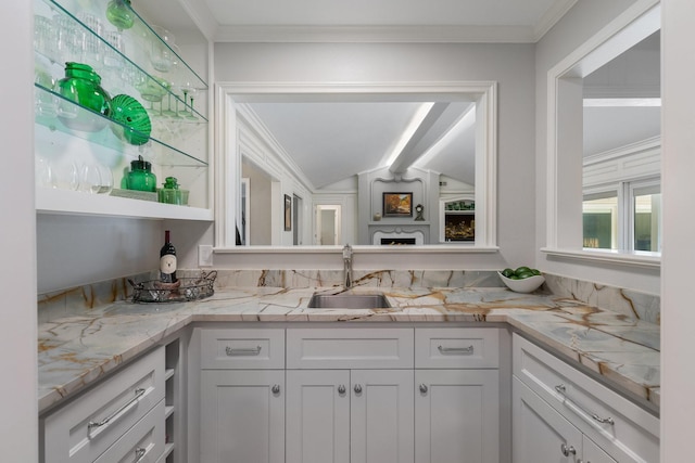 6867 Mossvine Dr, Dallas, TX 75254 - kitchen with a sink, white cabinetry, ornamental molding, vaulted ceiling, and light stone counters