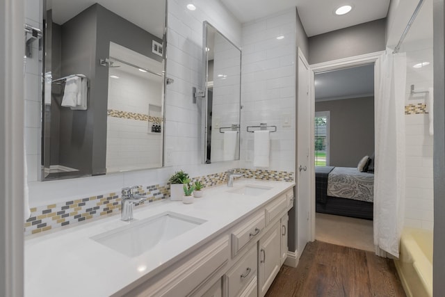 6867 Mossvine Dr, Dallas, TX 75254 - ensuite bathroom featuring wood finished floors, double vanity, tasteful backsplash, recessed lighting, and shower / tub combo