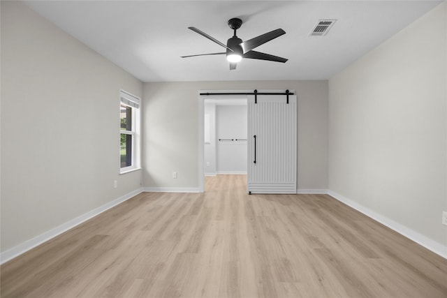 5305 Links Dr, Waco, TX 76708 - unfurnished bedroom featuring a barn door, light wood finished floors, baseboards, and a ceiling fan