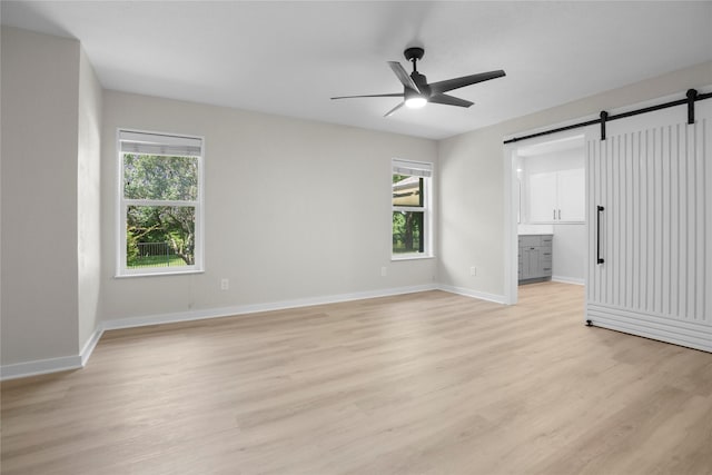 5305 Links Dr, Waco, TX 76708 - spare room featuring a barn door, light wood-style floors, a ceiling fan, and baseboards
