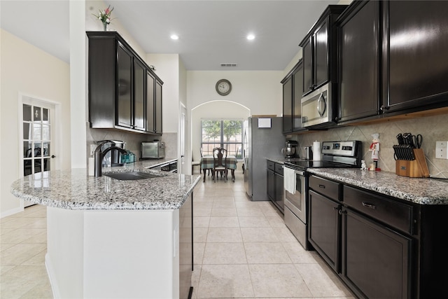 2014 Autumn Dr, Glenn Heights, TX 75154 - kitchen featuring stainless steel appliances, light tile patterned flooring, arched walkways, backsplash, and a peninsula
