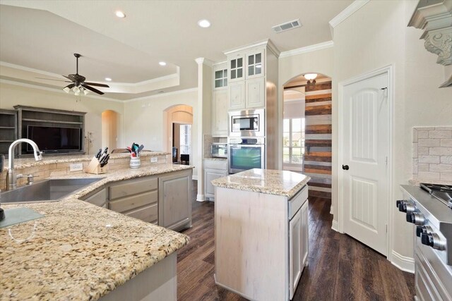 7030 Brooke Blvd, Midlothian, TX 76065 - kitchen with arched walkways, appliances with stainless steel finishes, a sink, ceiling fan, and a kitchen island