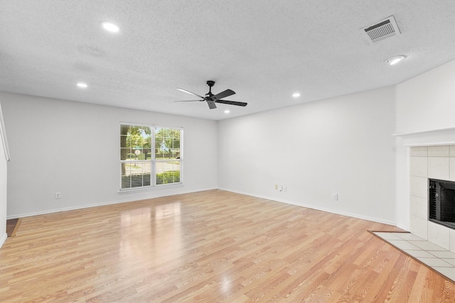 1800 Summer Glen Ct, Allen, TX 75002 - unfurnished living room featuring a ceiling fan, recessed lighting, a tile fireplace, light wood-type flooring, and a textured ceiling