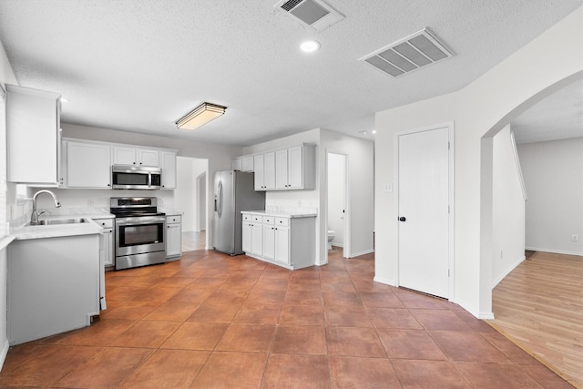 1800 Summer Glen Ct, Allen, TX 75002 - kitchen featuring appliances with stainless steel finishes, a sink, a textured ceiling, light countertops, and arched walkways