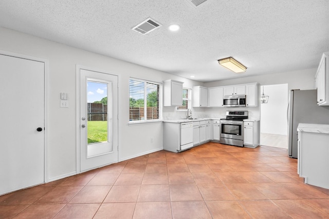 1800 Summer Glen Ct, Allen, TX 75002 - kitchen with stainless steel appliances, a textured ceiling, light tile patterned floors, white cabinets, and a sink