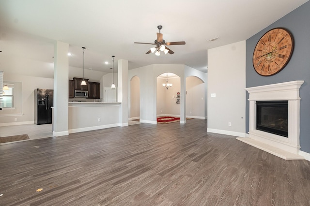 269 Arbury Dr, Forney, TX 75126 - unfurnished living room featuring arched walkways, a ceiling fan, a glass covered fireplace, and dark wood-style floors