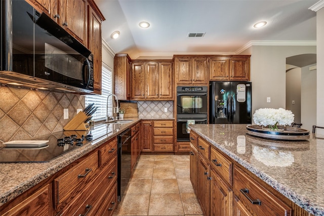 417 Fox Trl, Allen, TX 75002 - kitchen featuring black appliances, a sink, arched walkways, brown cabinetry, and light stone counters
