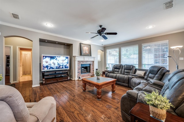 417 Fox Trl, Allen, TX 75002 - living room with arched walkways, a ceiling fan, a brick fireplace, dark wood-style floors, and crown molding