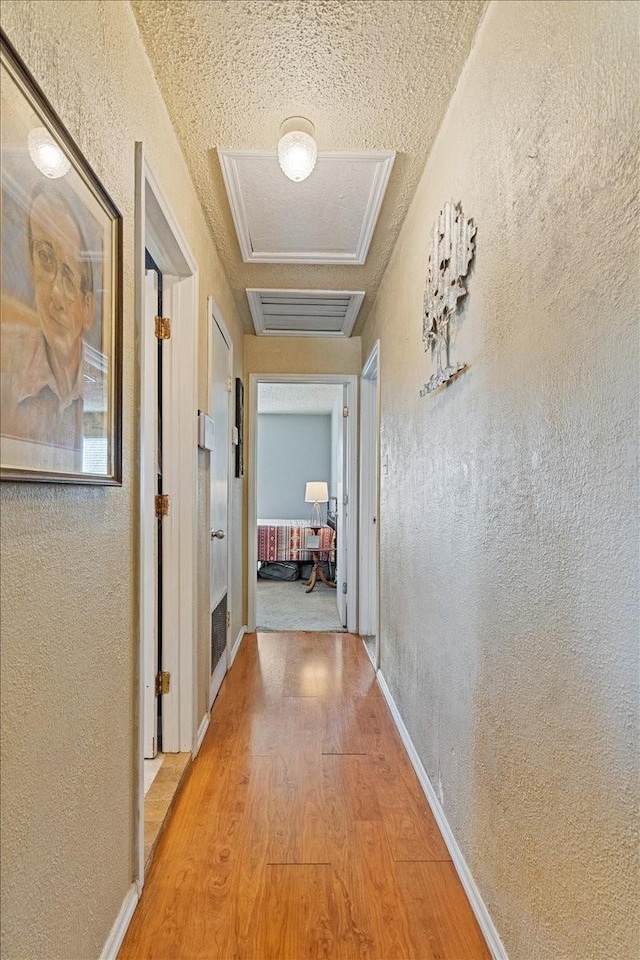 1320 Laredo Dr, Granbury, TX 76048 - corridor with light wood-type flooring, a textured wall, and attic access