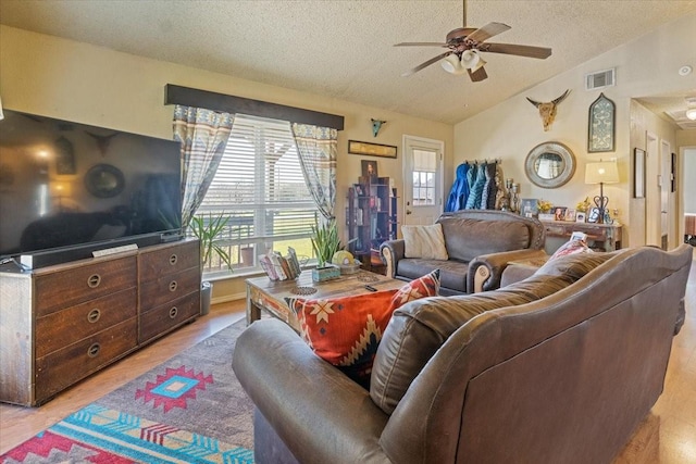 1320 Laredo Dr, Granbury, TX 76048 - living room featuring a textured ceiling, plenty of natural light, a ceiling fan, lofted ceiling, and light wood-style flooring